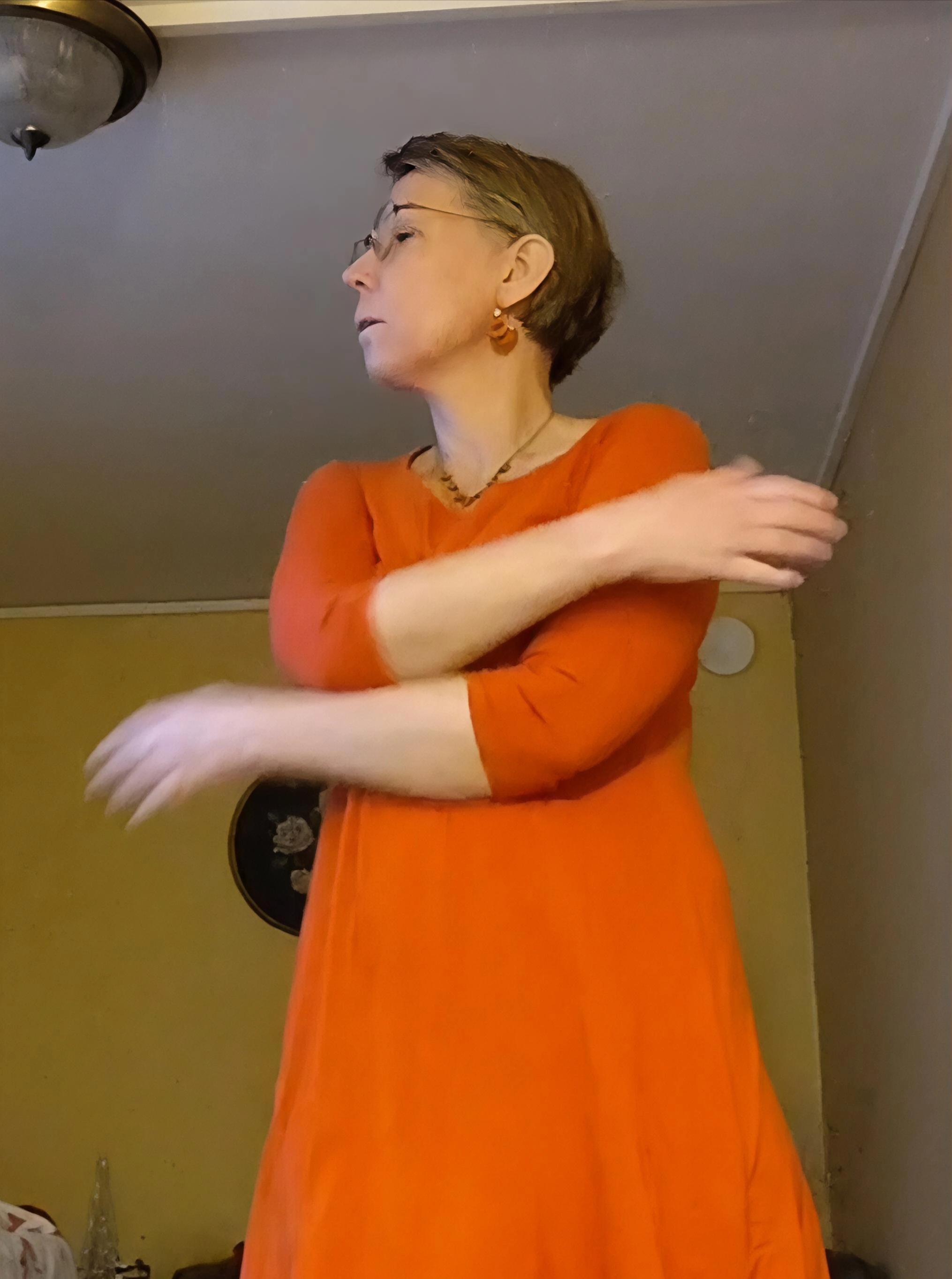 Nainen oranssissa mekossa, joka heiluttaa käsiään rentoutumisen saamiseen. 